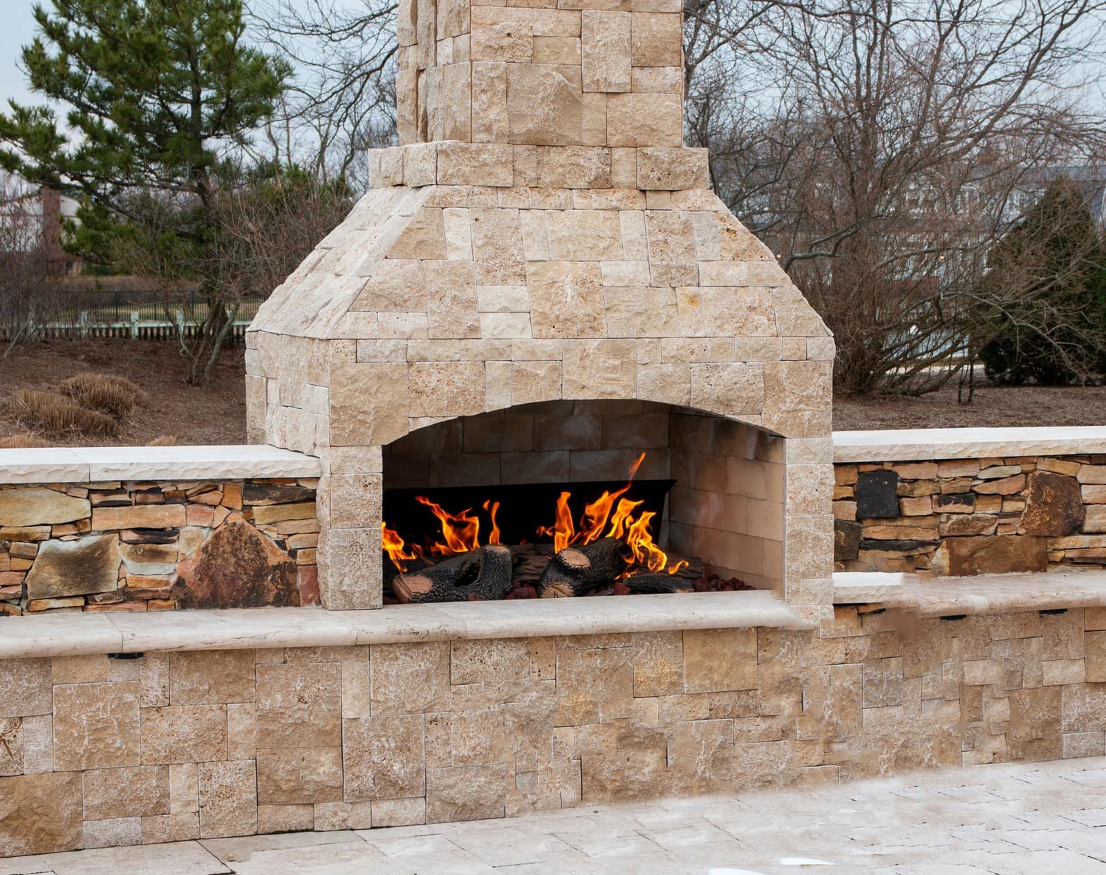Stone outdoor fireplace with a wood fire