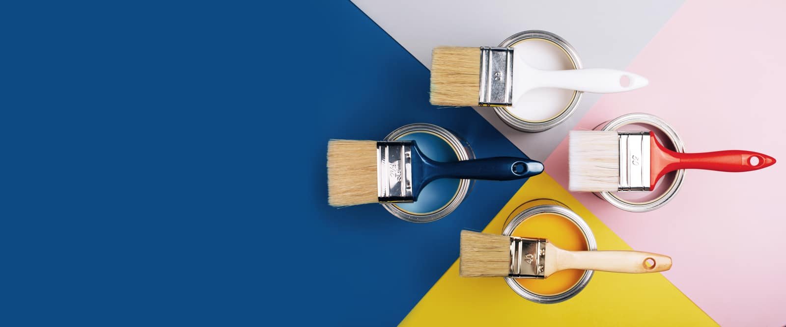 Paint cans and brushes on a blue and yellow surface