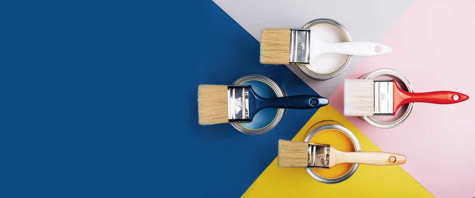 Paint cans and brushes on a blue and yellow surface